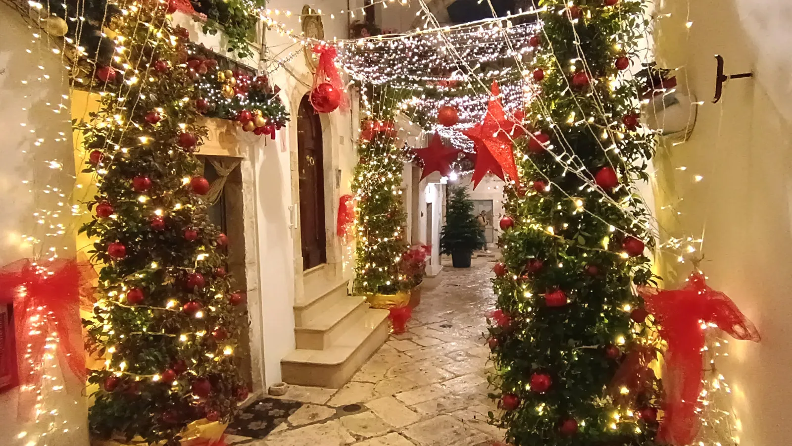 Locorotondo natale, alberi di natale con addobbi luminosi in vicolo del centro storico di locorotondo