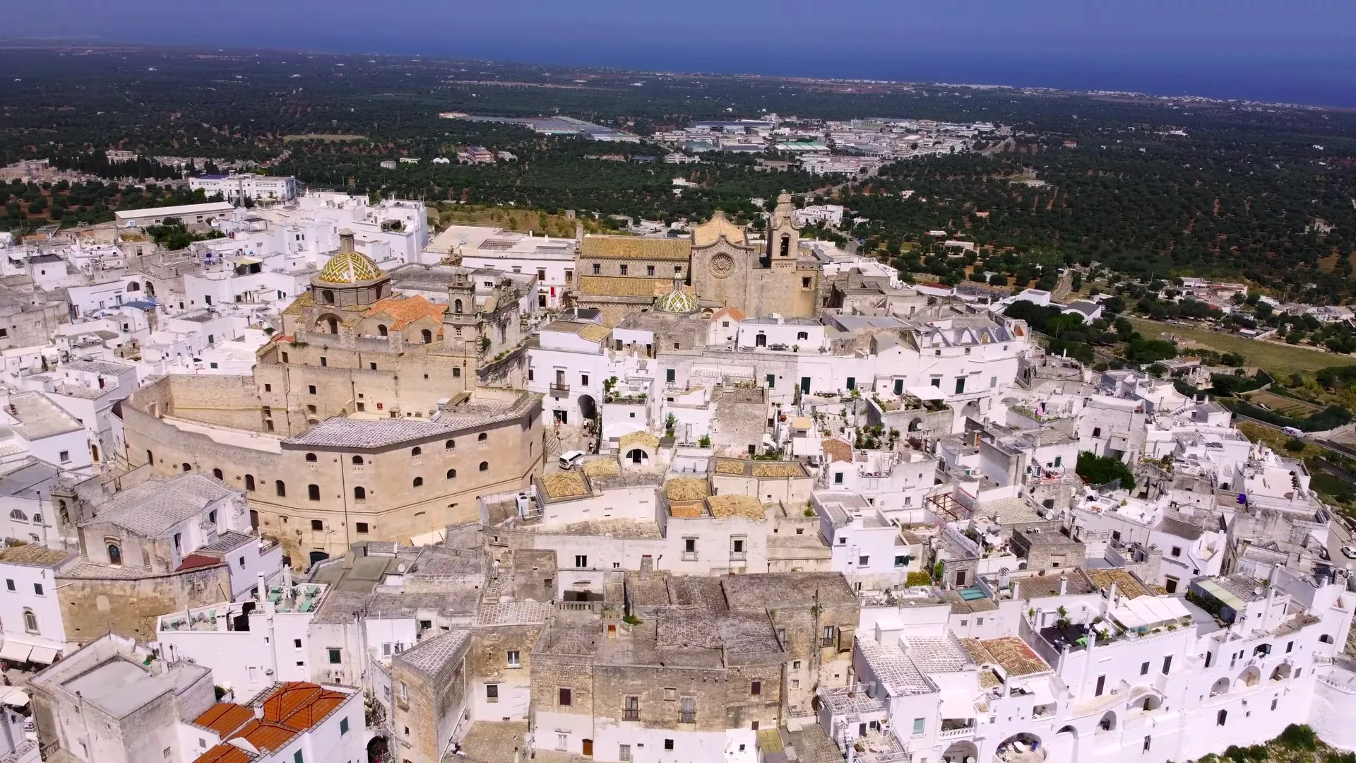 Ostuni center, aerial view of the historic center with olive groves and sea in the background